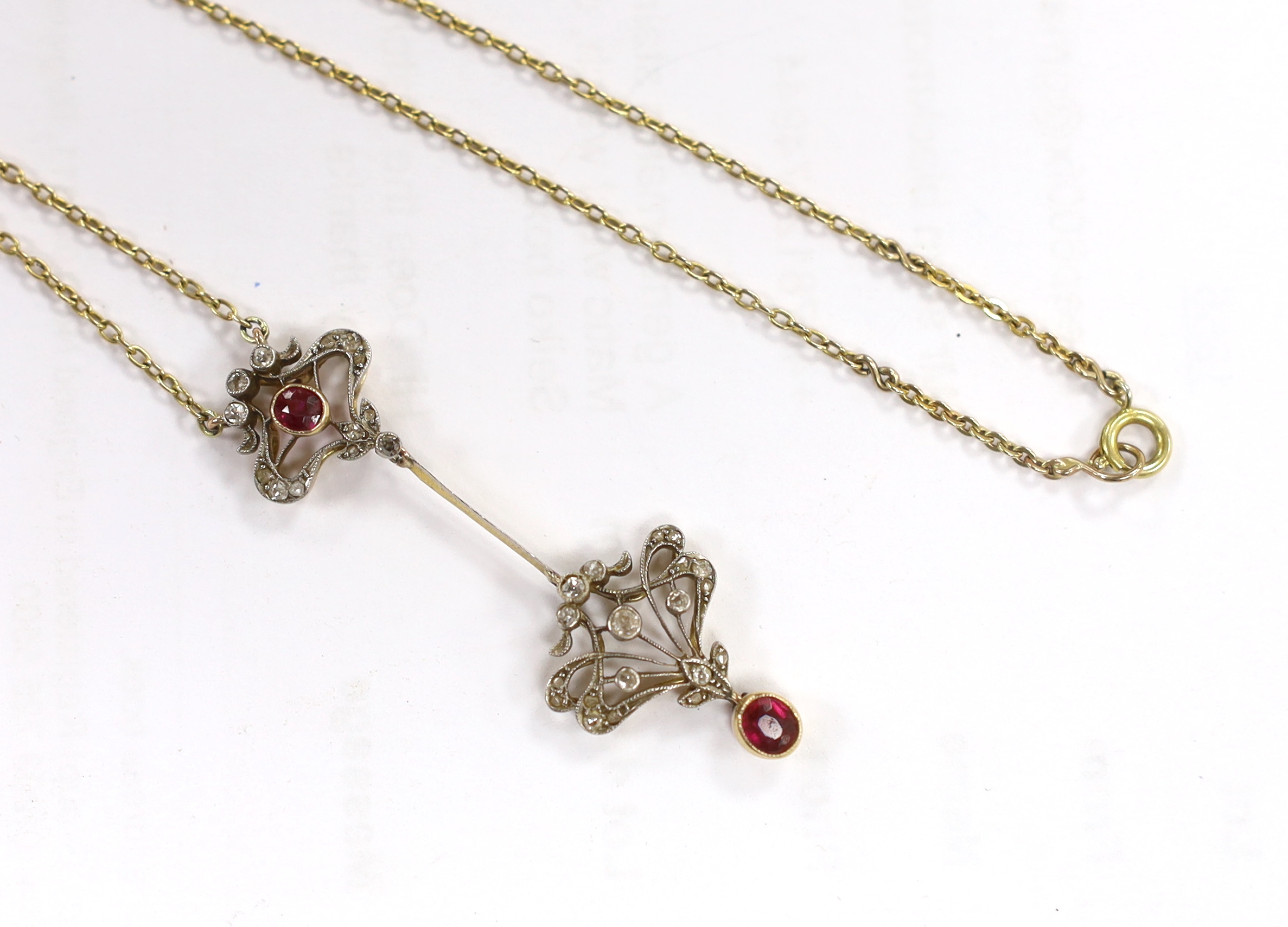 A Belle Epoque yellow metal and millegrain set ruby and diamond drop pendant necklace, the chain bale stamped 9ct, pendant 46mm, chain 47cm, gross weight 5.4 grams.